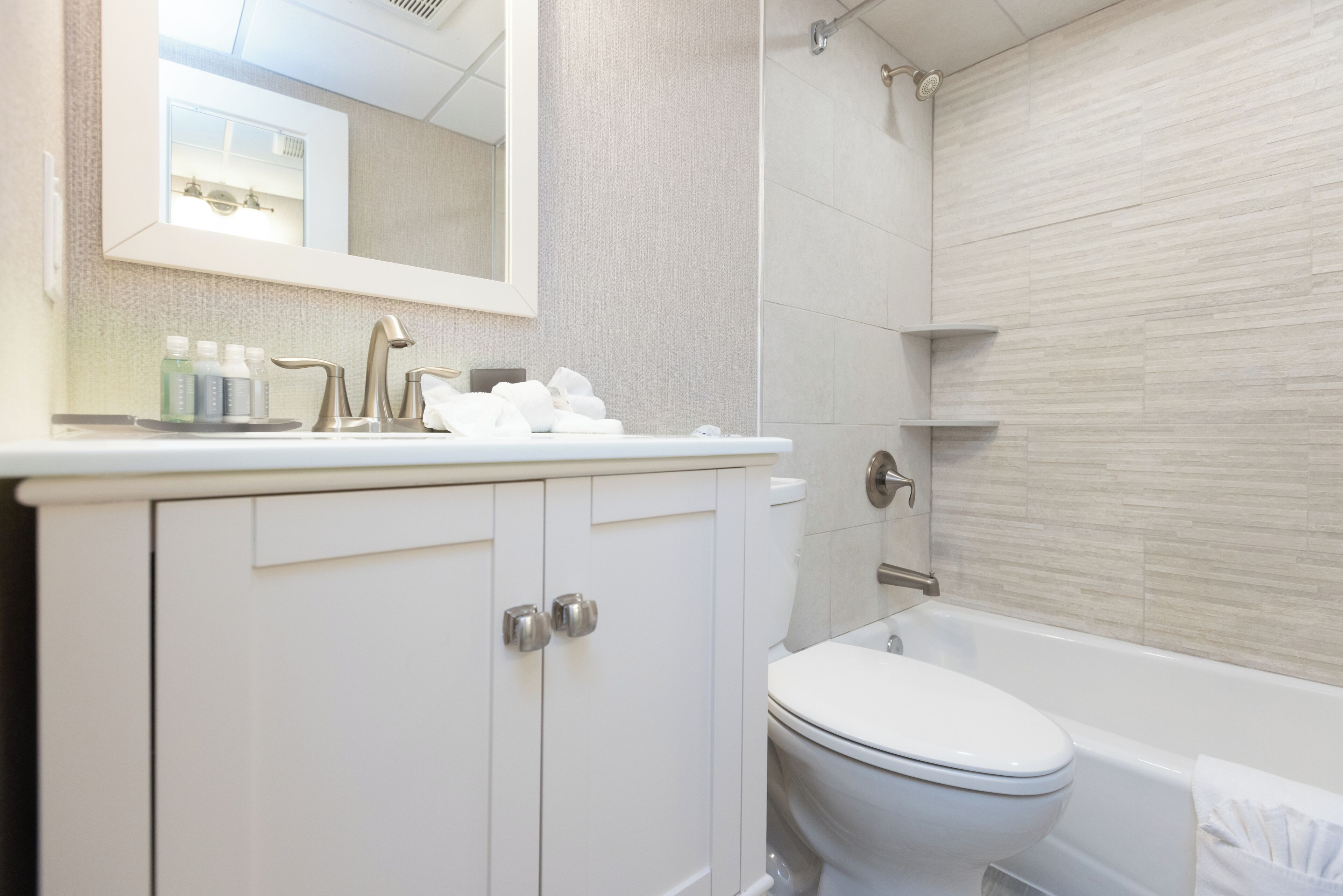 A bathroom with a white sink, mirror, and toilet.