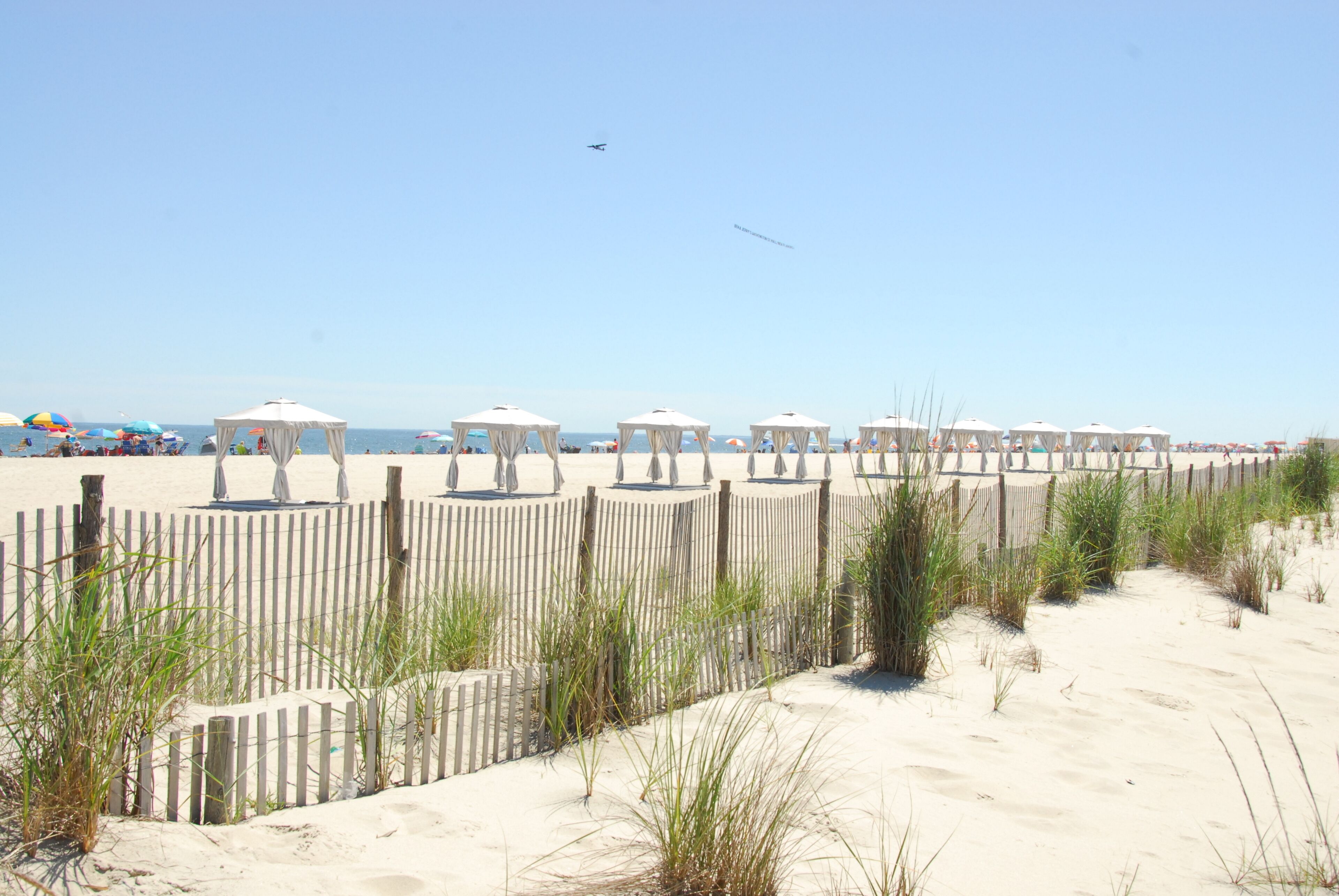 Una spiaggia con tende bianche e un recinto in legno.
