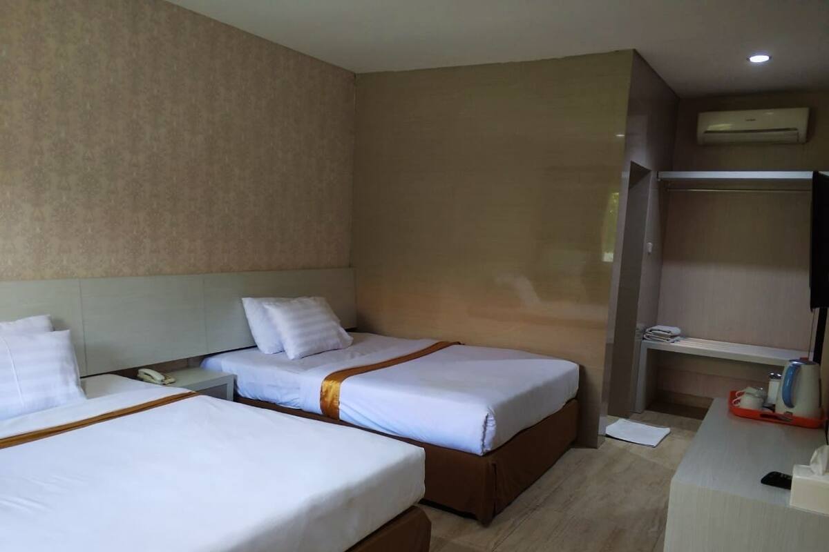 Ein Hotelzimmer mit zwei Betten, einem Schreibtisch und einem Kleiderschrank.