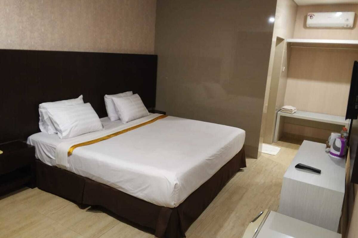 Ein Hotelzimmer mit Bett, Nachttisch und Fernseher.