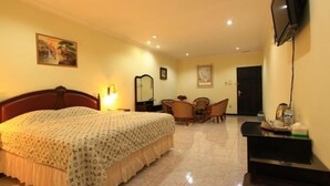 Una habitación de hotel con una cama, un escritorio con silla, un televisor montado en la pared y una puerta.