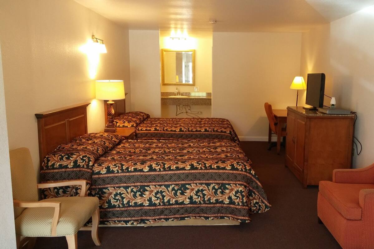 Hotellihuone, jossa on kaksi sänkyä, työpöytä, tuoli, peili ja televisio.