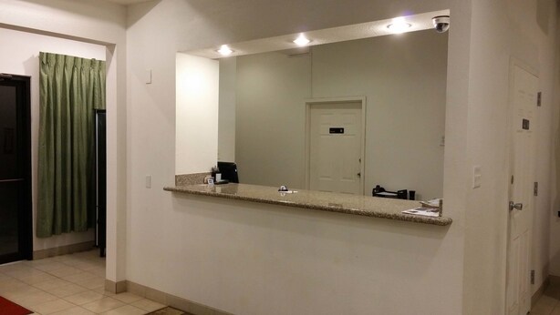 A hotel bathroom with a large mirror, a countertop, and a door. - Country Regency Inn & Suites (Manvel)