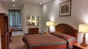 A hotel room with a bed, two bedside tables with lamps, a dresser, a mirror, and a window with curtains. - Country Regency Inn & Suites (Manvel)