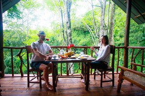 A wooden deck with a table set for two people, surrounded by lush greenery. - Ella Eco Lodge (Ella)