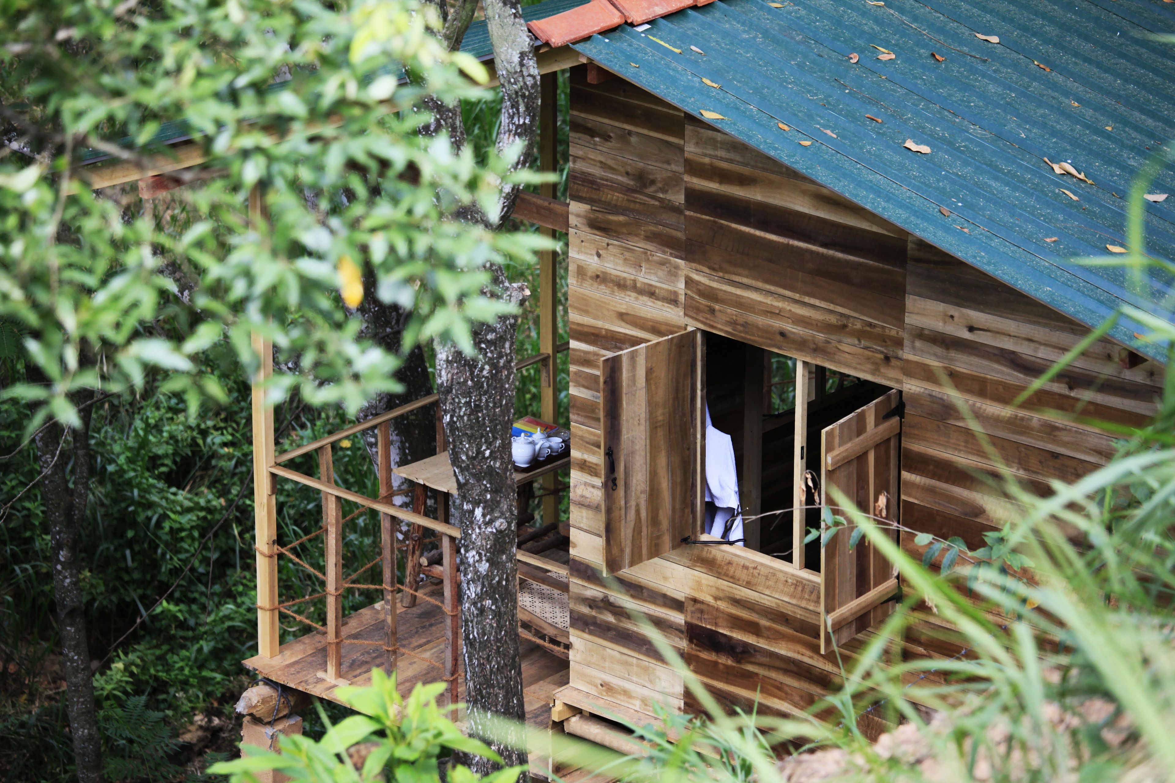 A wooden cabin with a balcony, surrounded by trees.