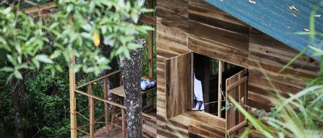 A wooden cabin with a balcony, surrounded by trees.