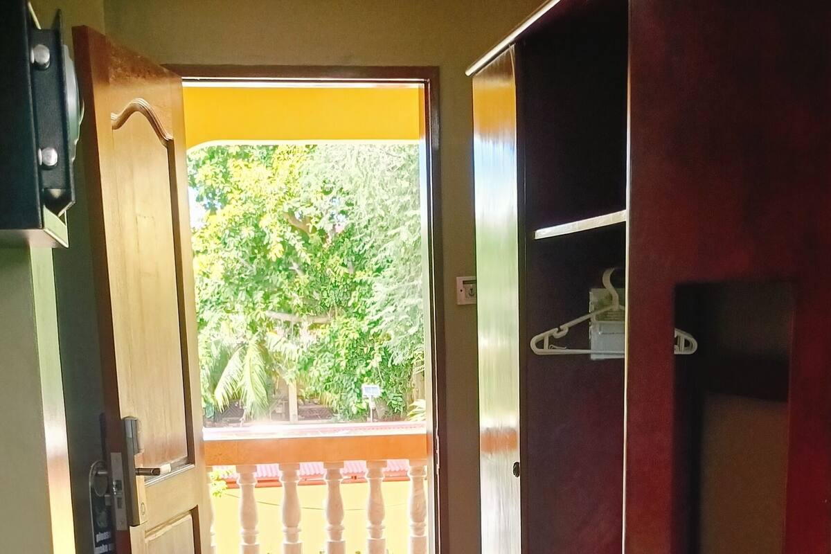 A hallway with a tiled floor leading to a balcony with a railing.