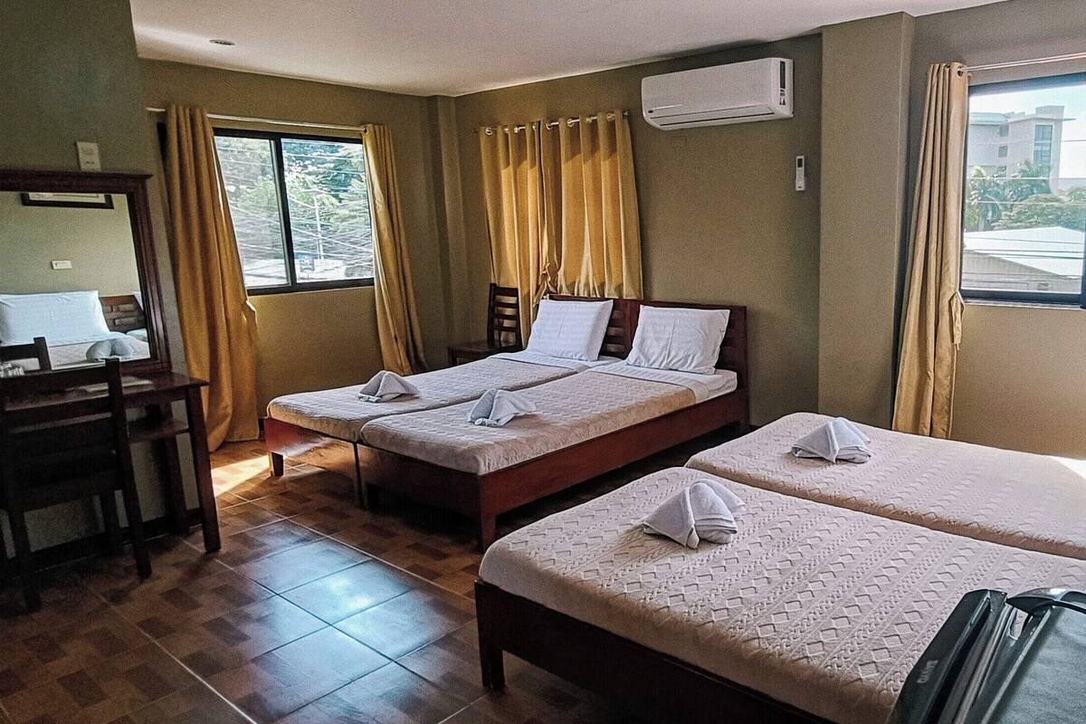 A hotel room with two beds, a desk, and a window with curtains.
