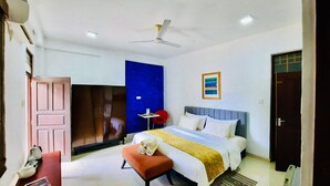 A bedroom with a bed, a desk, a chair, a wardrobe, a ceiling fan, and a door. - Hotel Dorset (Negombo)