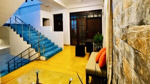 A modern interior with a blue staircase, a stone wall, and a seating area with orange cushions. - Hotel Dorset (Negombo)