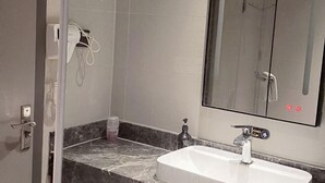 A bathroom with a marble countertop, a white sink, a glass shower enclosure, and a mirror with a built-in light. - Zunyue Grace Hotel (Shanghai Lida University Branch) (Shanghai)