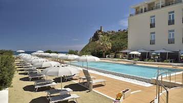 Relax by the ocean-view pool surrounded by sun loungers and lush greenery.