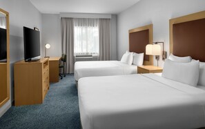 Quarto de hotel com duas camas, uma mesa de trabalho com televisão, uma cadeira, um abajur e uma janela com cortinas.