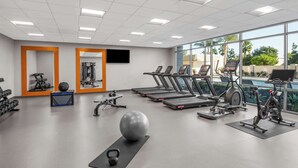 Un gimnasio con cintas de correr, pelotas de ejercicio y pesas.