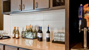Zona de bar con botellas de vino, copas, una grifería de cerveza y un enfriador de vino.