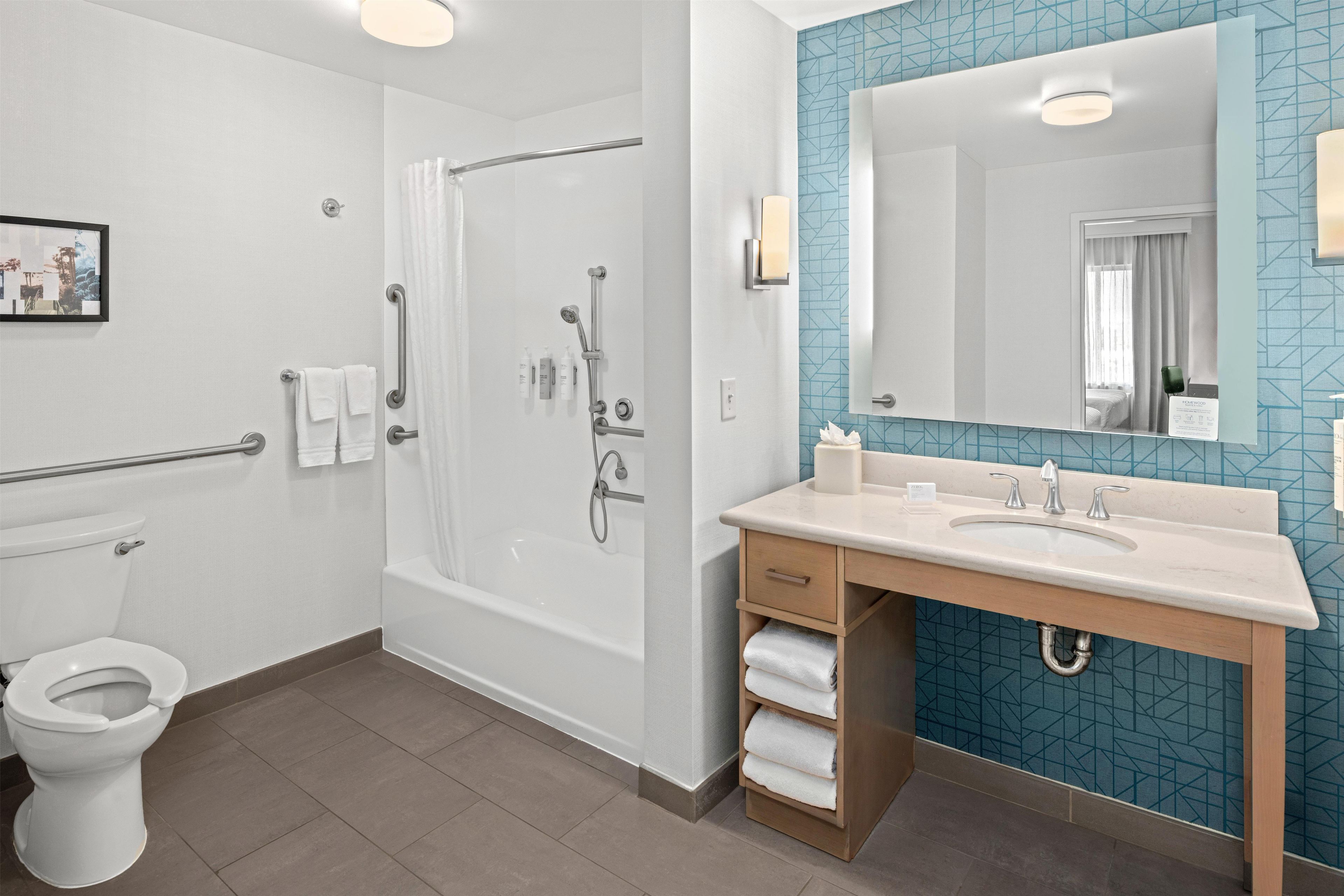 A modern bathroom with a bathtub, toilet, and vanity with a sink.