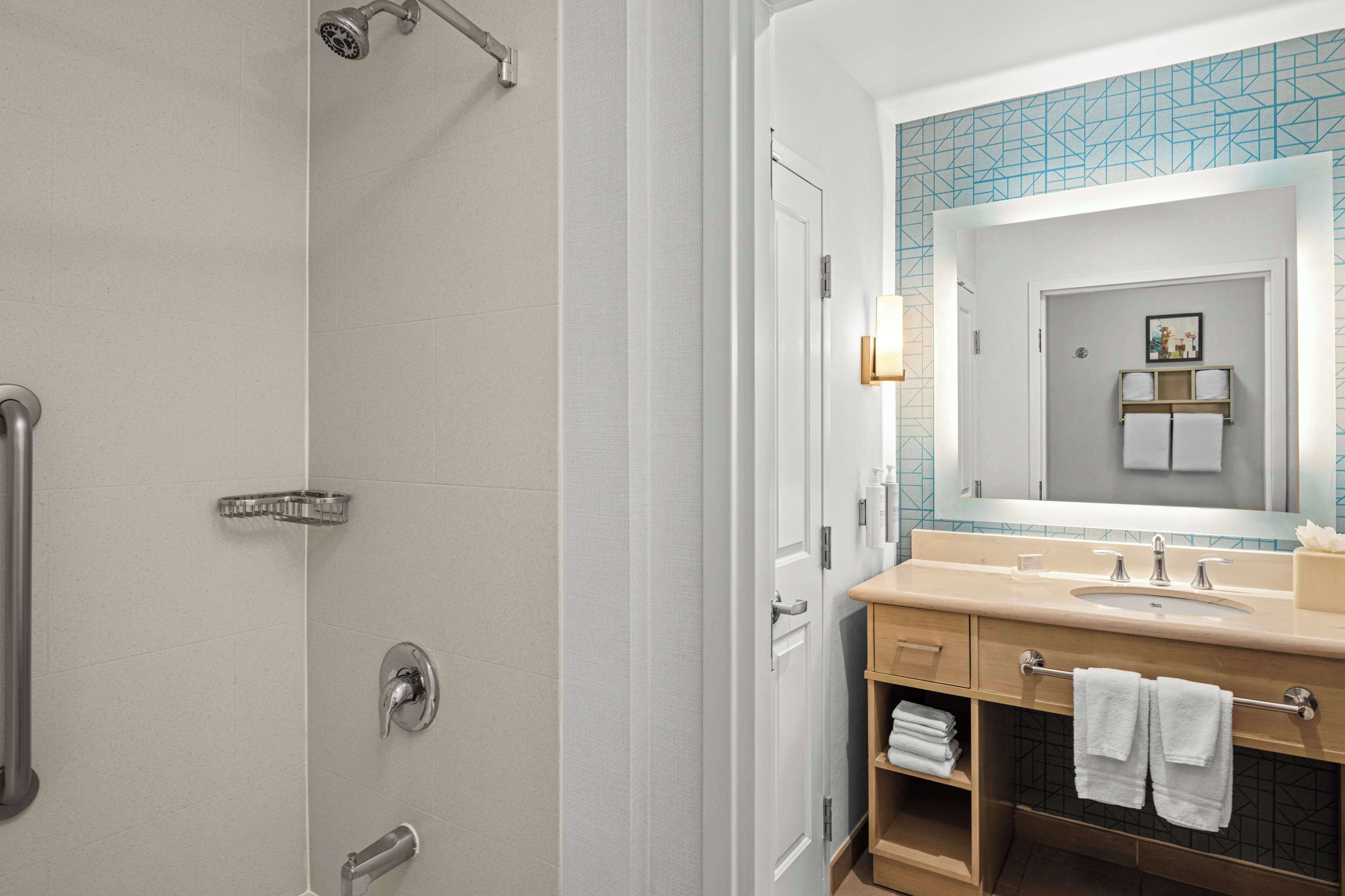A modern bathroom with a shower, a sink, and a vanity.