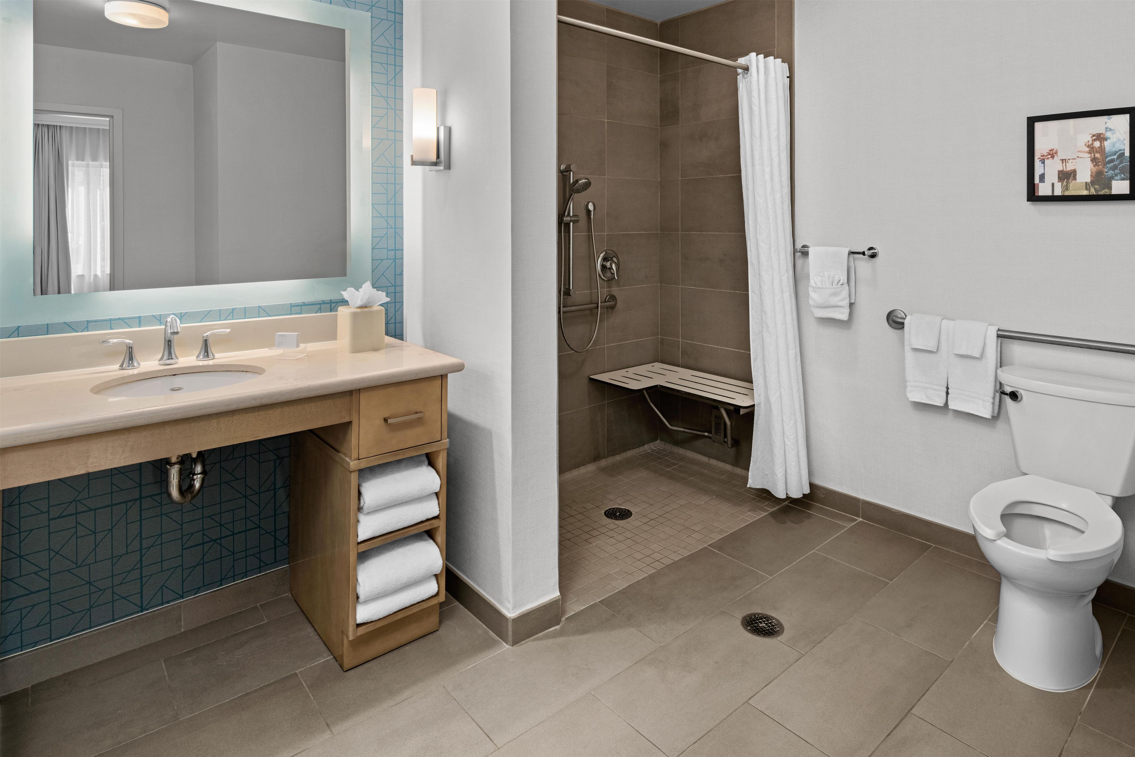 Un baño moderno con un espejo grande, lavamanos dobles, ducha y un inodoro.