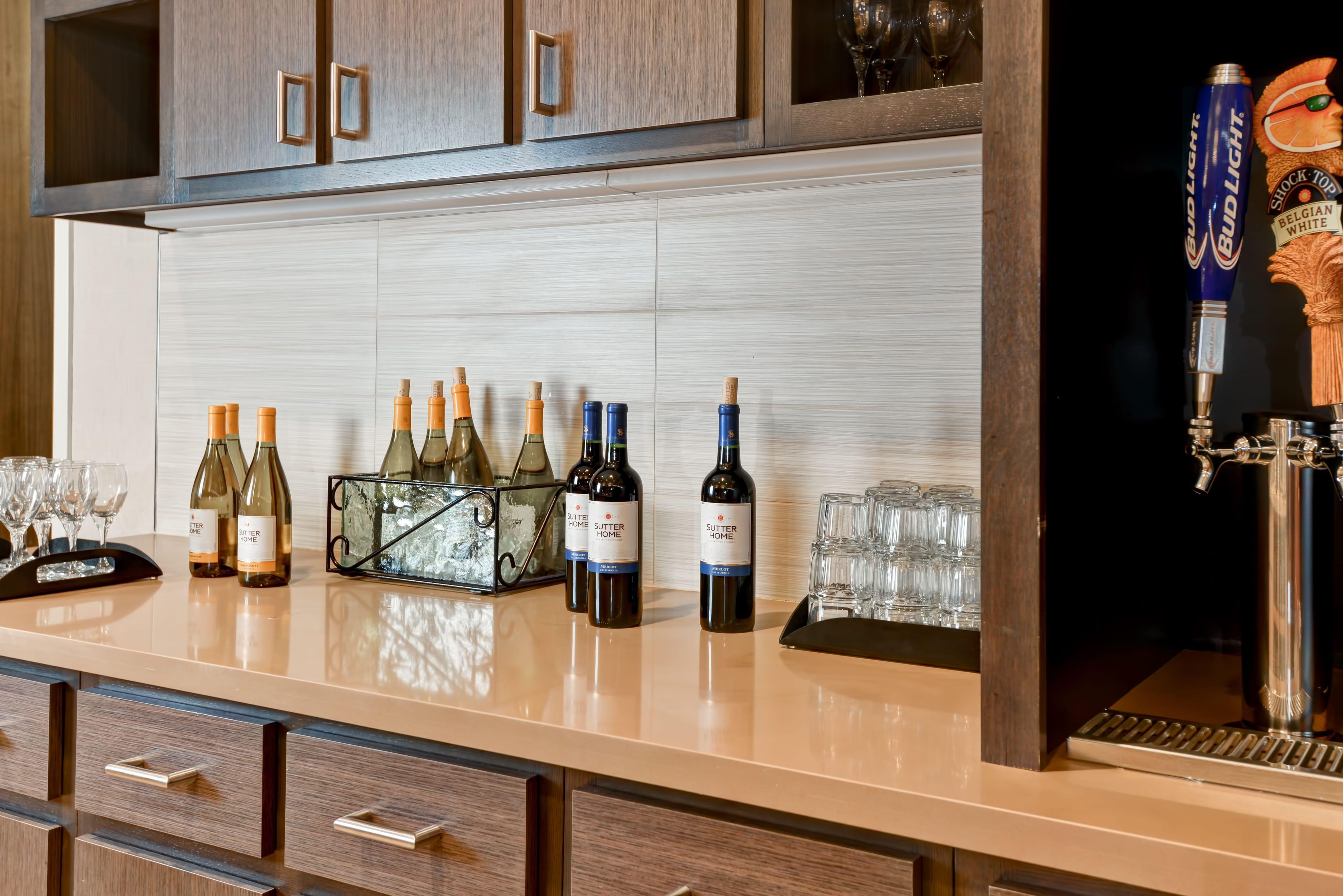 A bar area with wine bottles, glasses, and a beer tap.