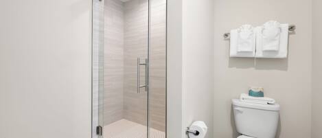Une salle de bain avec une douche à parois de verre, des toilettes et un porte-serviettes.