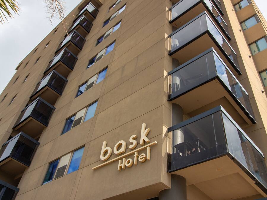 A tall hotel building with balconies and a sign that reads "bask Hotel".