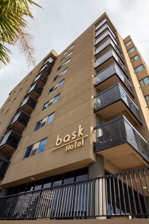 Een hoog hotelgebouw met balkons en een bord waarop staat 