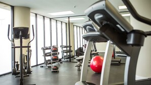 Une salle de sport équipée de divers appareils, notamment des tapis de course, des appareils de musculation et des ballons d’exercice.