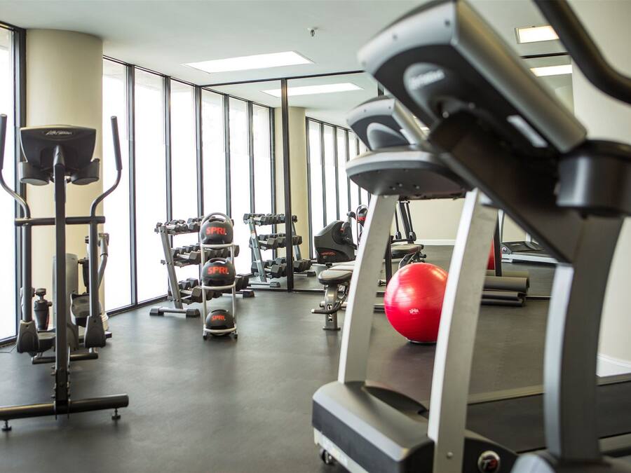 A gym with various exercise equipment, including treadmills, weight machines, and exercise balls.