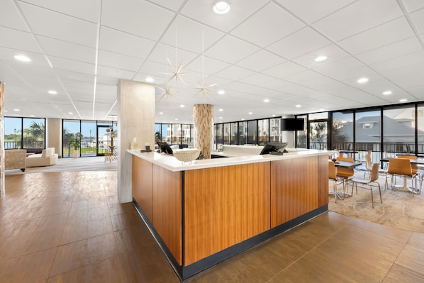 Una moderna zona de recepción con mostrador de madera, ventanas amplias y vistas al exterior.
