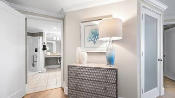 A hallway with a grey textured dresser, a white lamp, and a framed artwork on the wall.