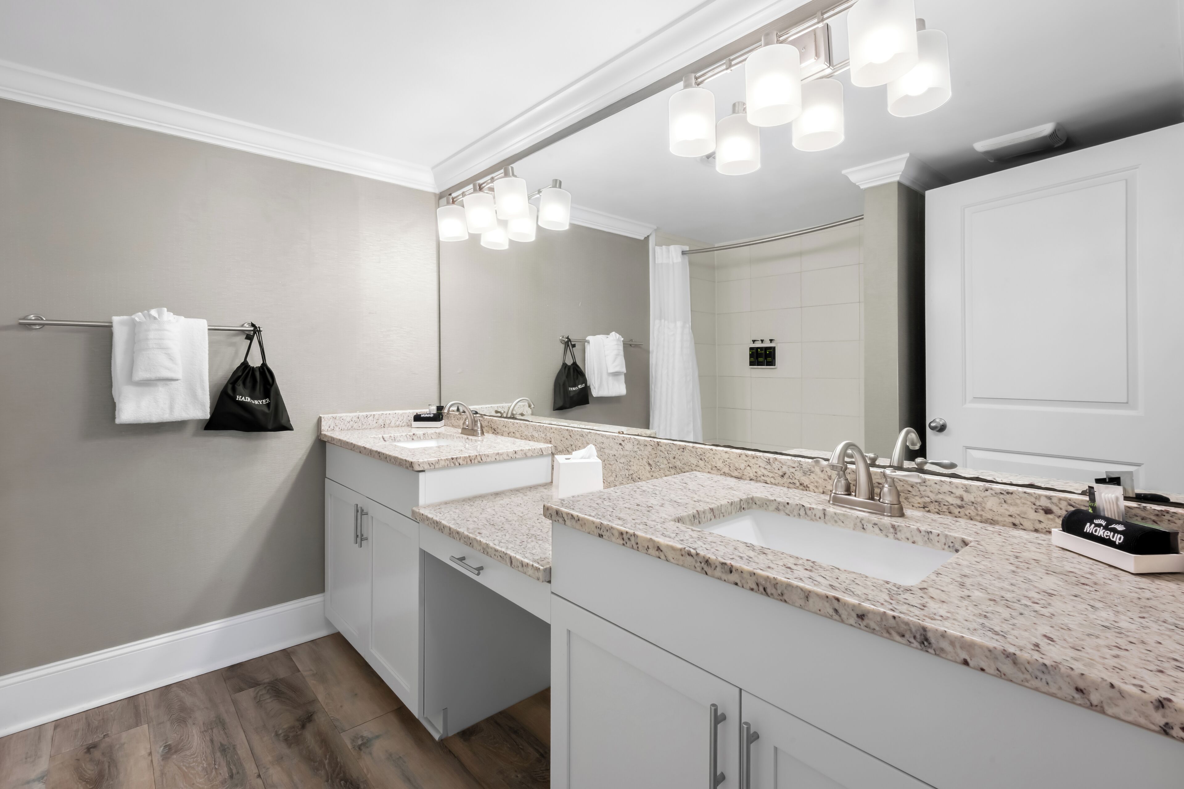 Une salle de bain avec deux lavabos, un grand miroir et un porte-serviettes.