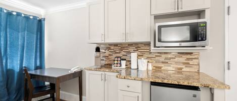 A compact kitchen with white cabinets, a microwave, a coffee maker, and a dishwasher.