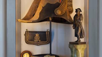 A display case containing a large hat, a statue, a pocket watch, and framed portraits.