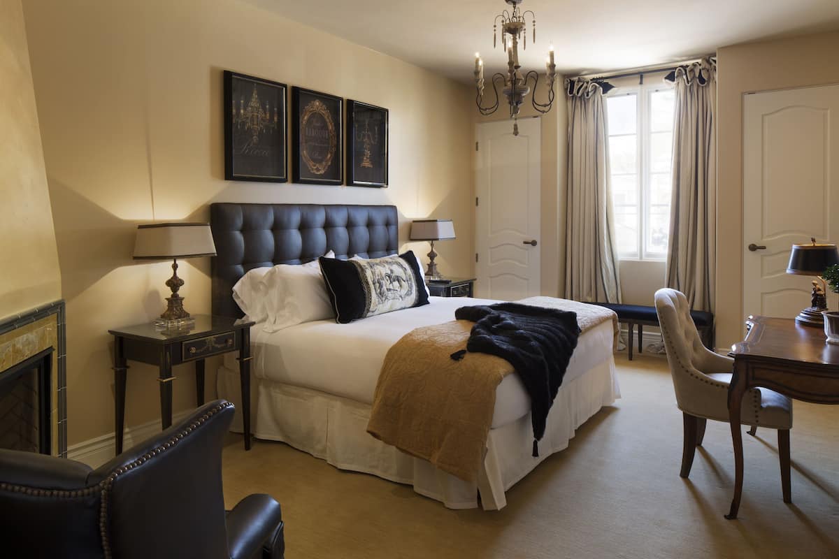A neatly arranged bedroom with a large bed, bedside tables, a chair, and a desk.