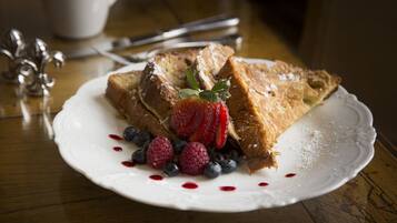 A plate of French toast with strawberries and blueberries on a white plate.