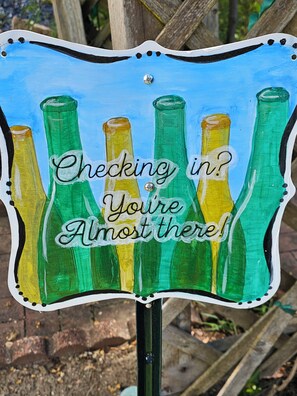 A sign with green and yellow bottles and the text "Checking in? You're Almost there!"