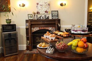 A breakfast buffet with eggs, pastries, and a fruit bowl.