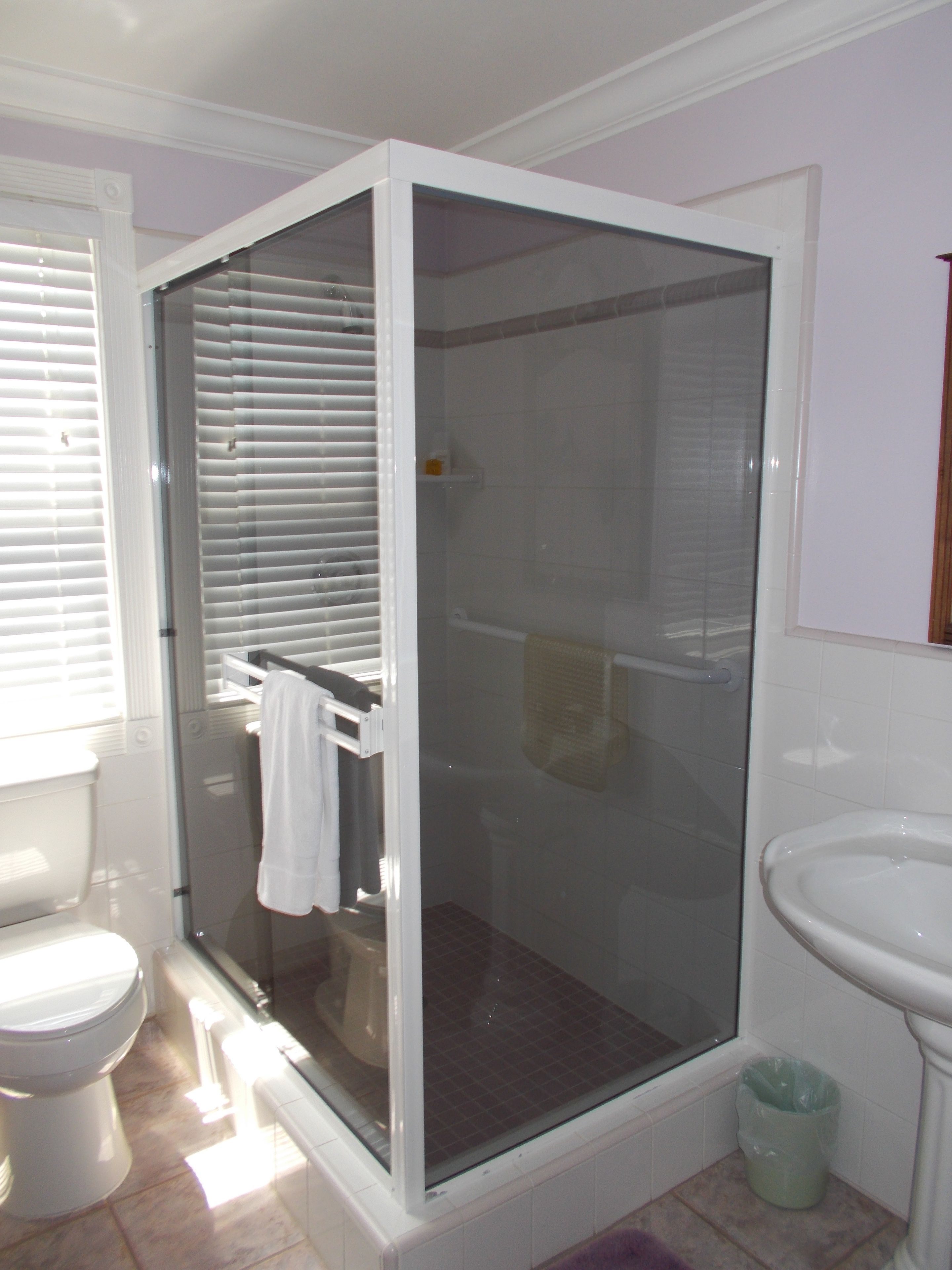 A bathroom with a glass-enclosed shower, a toilet, and a sink.