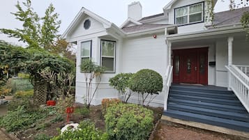 A two-story white house with a red front door, a small front garden, and a brick pathway leading to the entrance.