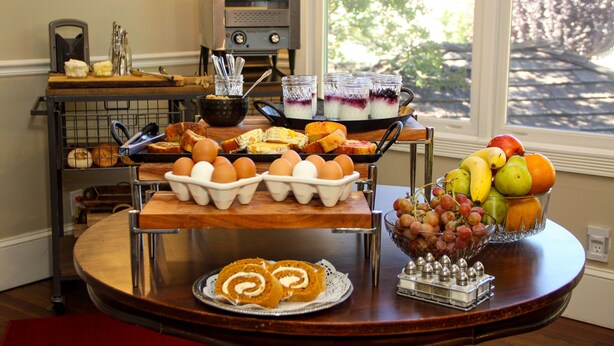 Un bufé de desayuno con huevos, pasteles y un bol de fruta.