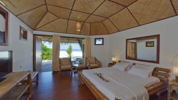 Una habitación con una cama grande, muebles de madera, un televisor y vista al océano.