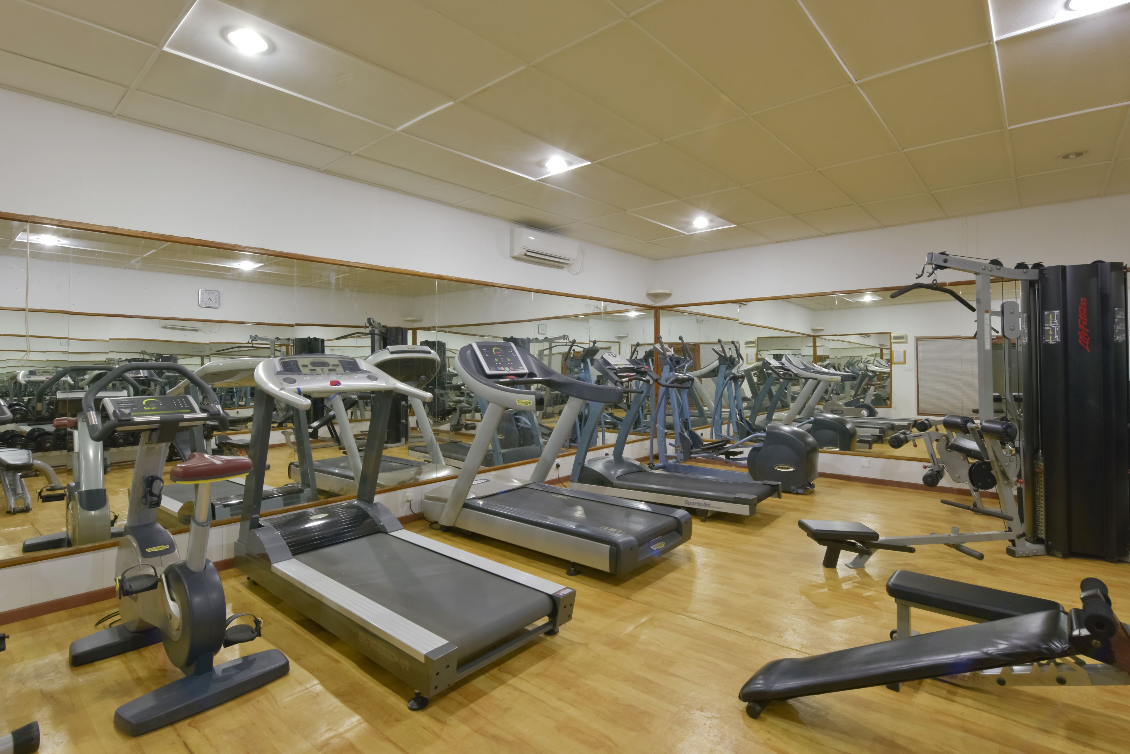 Un gimnasio con cintas de correr, bicicletas estáticas y máquinas de pesas.