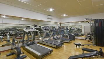 Un gimnasio con cintas de correr, bicicletas estáticas y máquinas de pesas.
