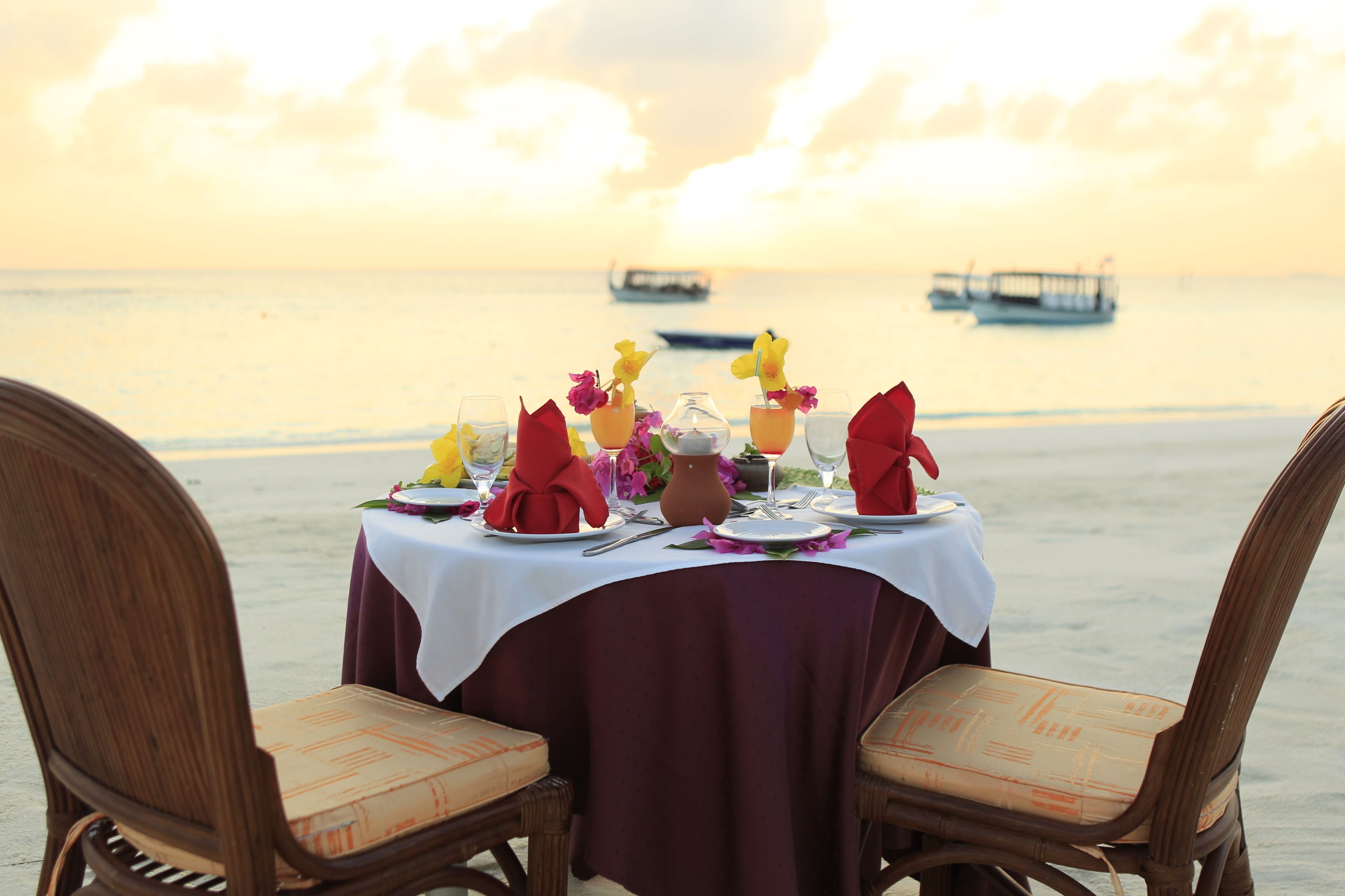 Ein Tisch für zwei Personen mit Blick auf das Meer und Boote im Hintergrund.