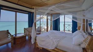 Habitación con cama bajo un dosel, muebles de madera y vistas al mar.