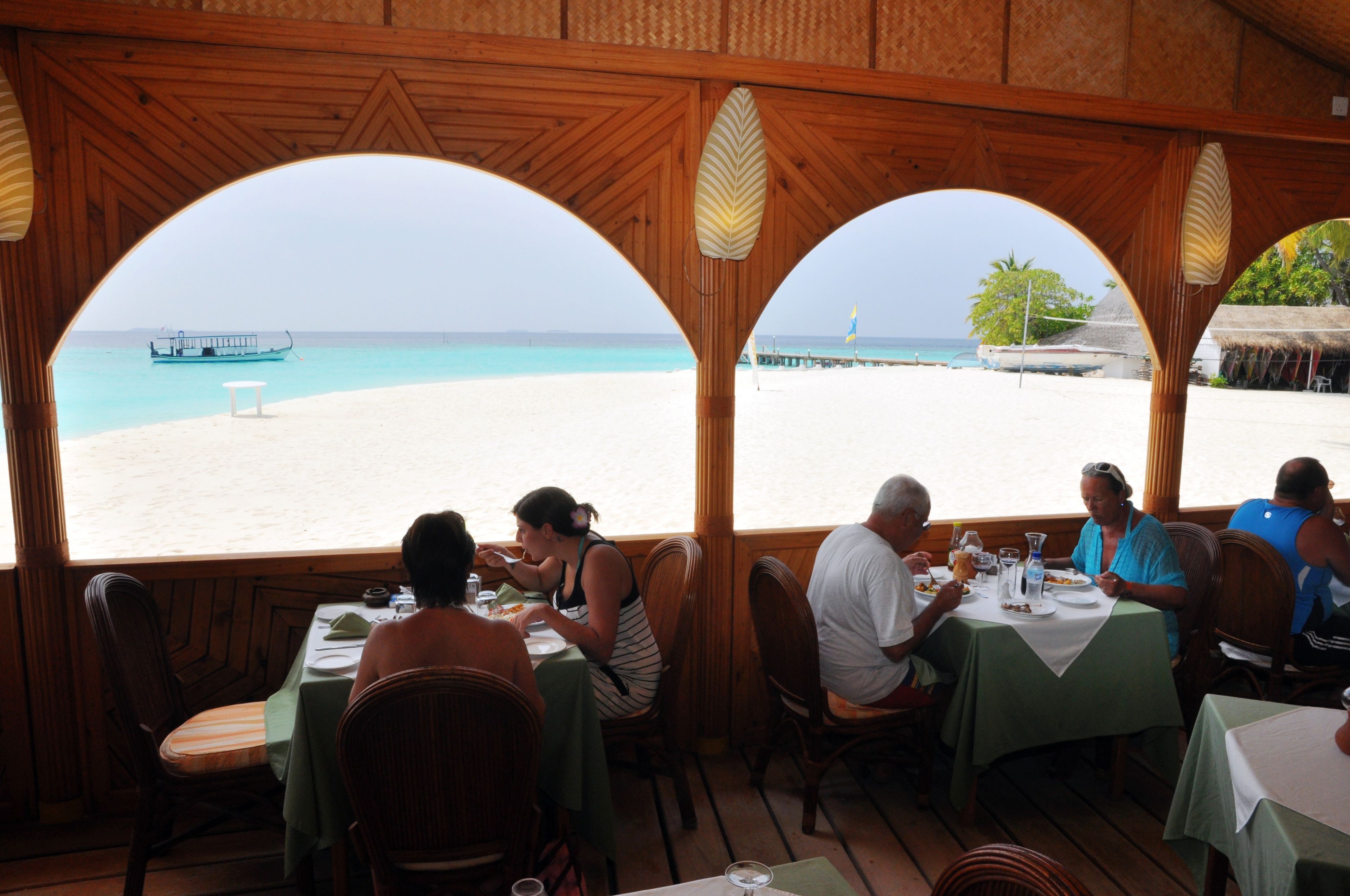 Un restaurante con arcos de madera y vistas a la playa.