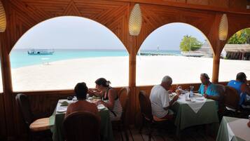 Un restaurante con arcos de madera y vistas a la playa.