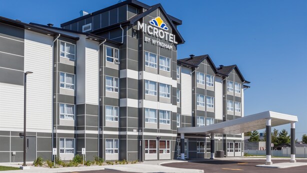 A modern Microtel by Wyndham hotel with a covered entrance and multiple floors. - Microtel by Wyndham Casselman (Casselman)