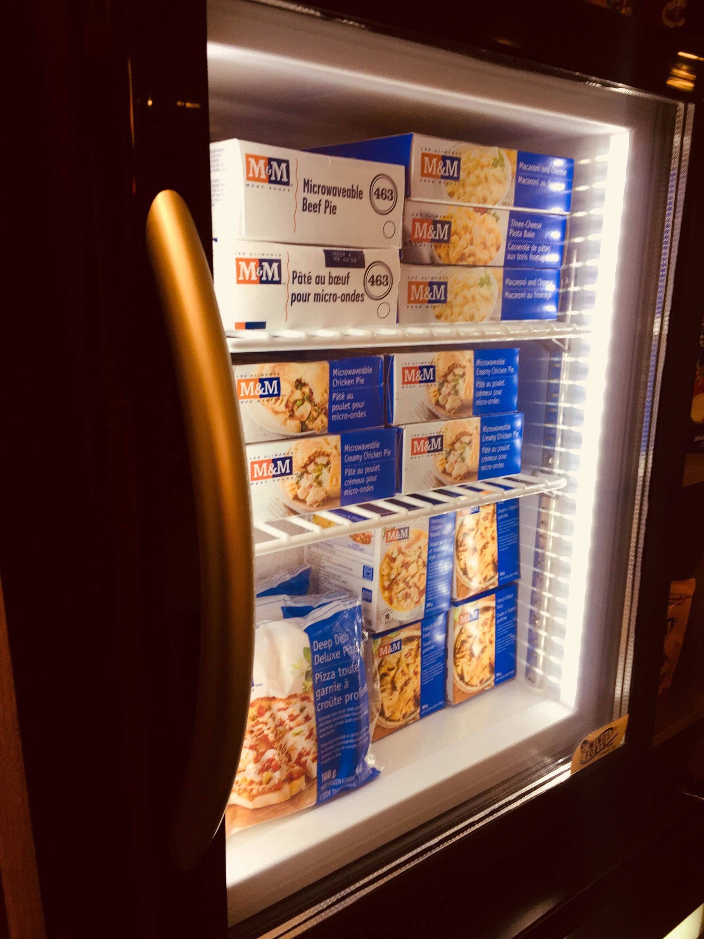 A refrigerated display case with various packaged food items, including boxed meals and pizza.